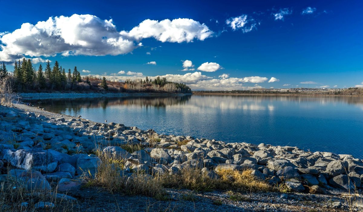 Calm water and a rocky shoreline under a blue sky